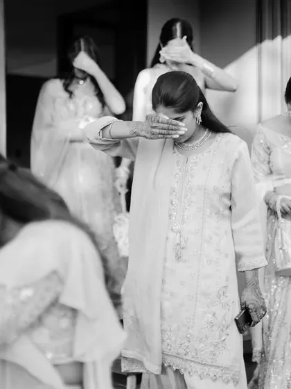 A candid black and white photo capturing the emotional 'vidaai' ceremony, where the bride's family tearfully says goodbye. This raw, unposed moment is a powerful example of documentary wedding photography.