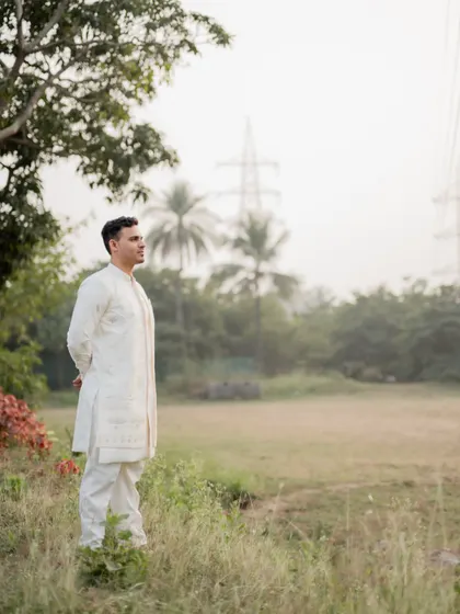 A solo portrait of the groom-to-be, looking thoughtful in a serene outdoor setting during his engagement photoshoot.
