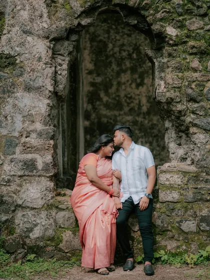 A tender kiss on the forehead, framed by the arch of ancient stone ruins.