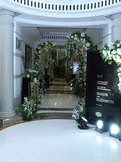 A chic and modern welcome area in black and white. The custom signage for Shaun and Elizabeth is flanked by dramatic floral arrangements, setting a sophisticated and contemporary tone for their celebration.