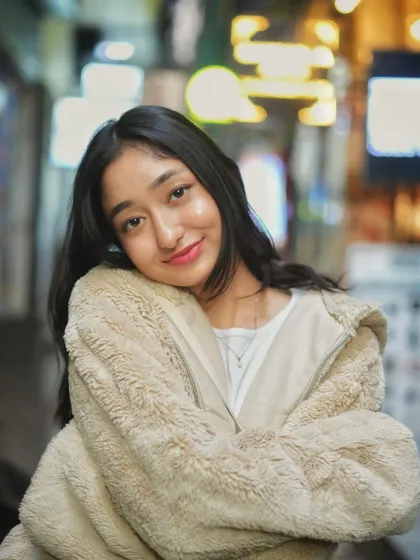 A relaxed and happy pose, leaning into her shoulder. This shot captures a moment of comfort and joy, with the city lights providing a warm, dreamy backdrop.