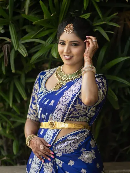 A duplicate of image 105, a close-up of the bride in her royal blue Banarasi saree and intricately embroidered blouse.
