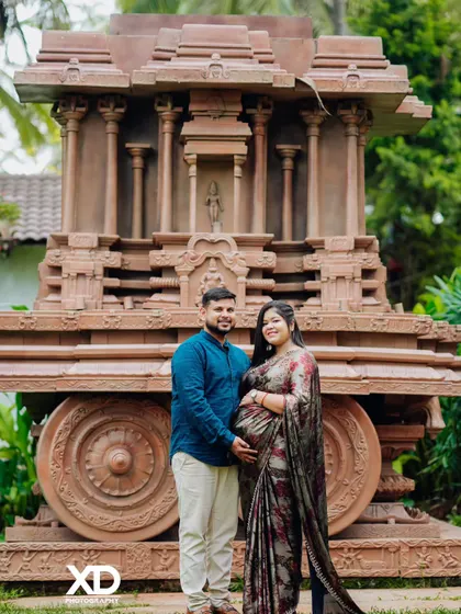 A proud couple stands together before the stone chariot, a symbol of strength and heritage.
