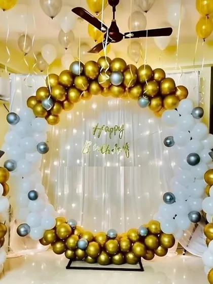 I transformed this living room into an elegant party space with a classic gold, white, and silver theme. The design includes a circular balloon frame perfect for photos, set against a backdrop of soft drapes and twinkling fairy lights. This shows how even a simple space can feel luxurious for a birthday.
