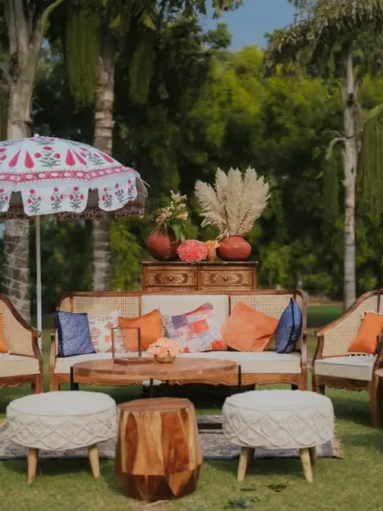 A comfortable lounge area with cane furniture, colorful cushions, and a hand-painted umbrella, creating a relaxed and stylish space for guests at the Mehendi.