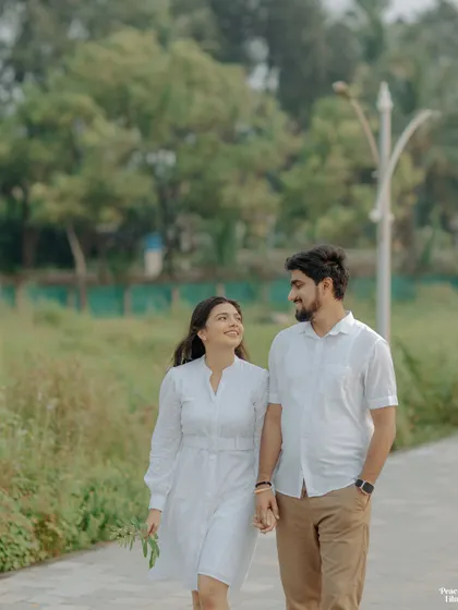 A simple walk in the park becomes a romantic pre-wedding moment. The couple's easy stride and shared smiles tell a story of comfortable, everyday love.