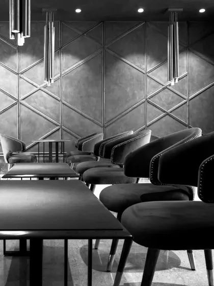 This black and white shot of the dining area emphasizes the strong geometric patterns and the play of light and shadow. The design creates a visual symphony that is both modern and timeless.