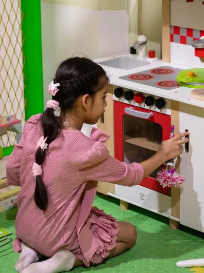 This little chef is busy in her play kitchen, which features a pretend stove, oven, and sink for realistic role-playing.