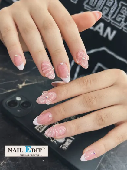 We love elevating a classic French manicure. This design on almond-shaped nails features intricate, hand-sculpted 3D elements, including delicate flowers and seashell textures, for a look that is both elegant and artistic.