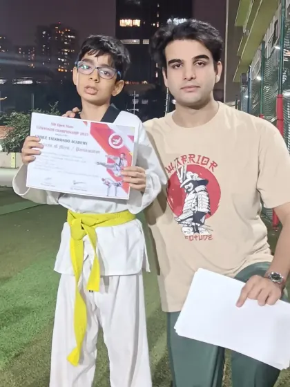 A student proudly holds his certificate from a Taekwondo championship. Every competition is a chance to grow.