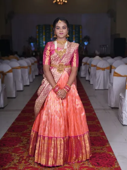 Another beautiful client at her half-saree function, wearing a peach and pink Langa Dhawani with a richly embroidered blouse.