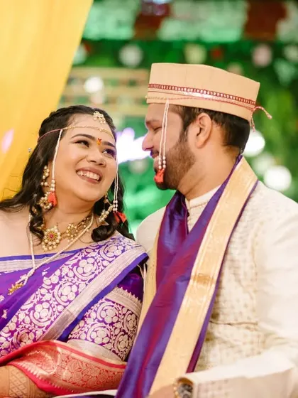 A lovely portrait of the couple seated together, their coordinated purple and white outfits looking vibrant against the yellow decor.