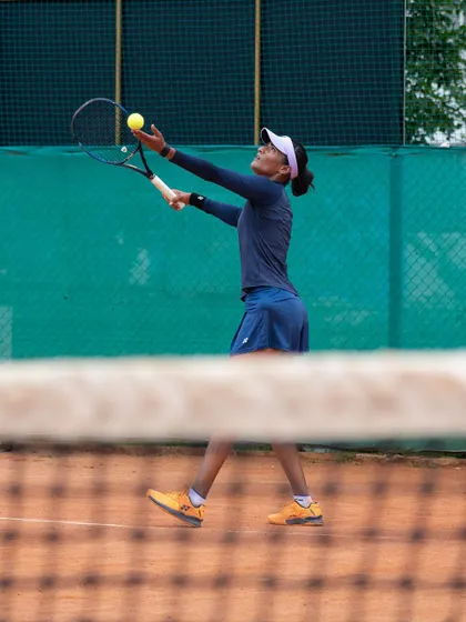 The service motion is one of the most critical parts of the game. Here, Rutuja is seen practicing her ball toss and racket positioning during a focused training session on a clay court.
