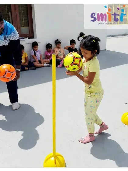 A coach guides a girl as she practices her ball skills. Individual attention helps children master new physical challenges.
