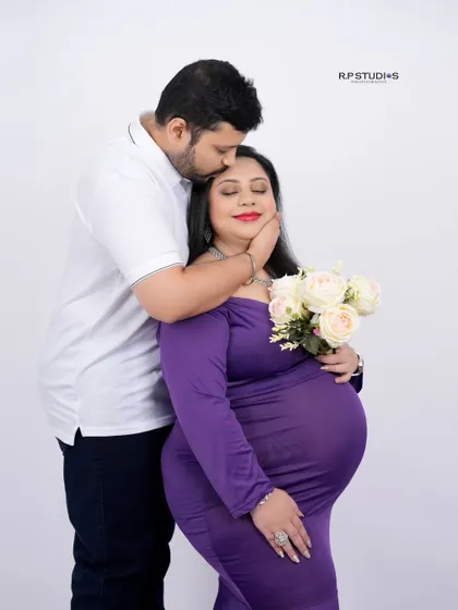 A tender moment between partners. The dad-to-be gently kisses his partner's forehead, a simple gesture full of love and support.