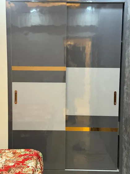 A close-up of a sliding wardrobe with a glossy grey, white, and gold design. The sleek look is perfect for a modern bedroom.