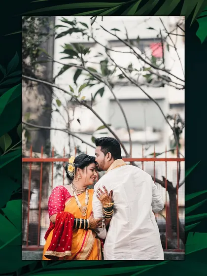 A sweet moment captured outdoors. The groom places a gentle kiss on his bride's forehead as she smiles, her traditional attire beautiful against the natural backdrop.