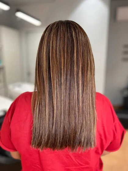 Golden bronze highlights on straight hair. This shows the precision of the highlight application, creating beautiful, distinct ribbons of color.