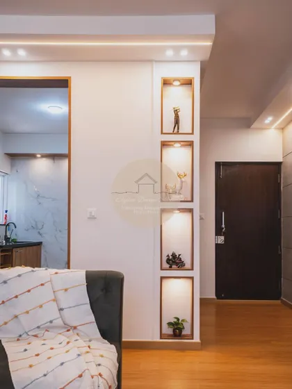 A contemporary 3BHK home at Godrej Air, Hoodi. This living area features clean lines, recessed niche shelving with spotlights, and warm wooden flooring, creating a space that is both modern and timeless.