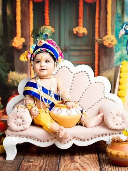 A majestic portrait of a baby dressed as Kanha, sitting on a miniature throne. The entire set is designed to evoke the stories of Lord Krishna.