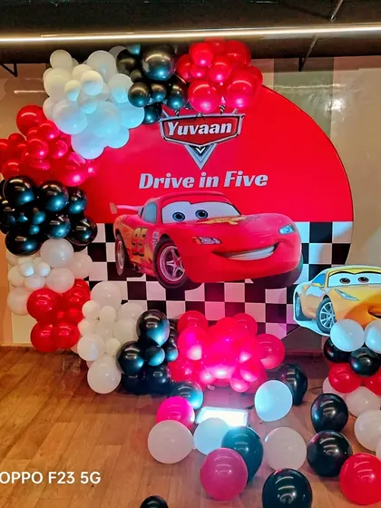 Kachow! We raced to create this "Drive in Five" Cars theme for Yuvaan's 5th birthday. The setup features a circular backdrop with Lightning McQueen, a checkered flag motif, and a red, black, and white balloon garland.