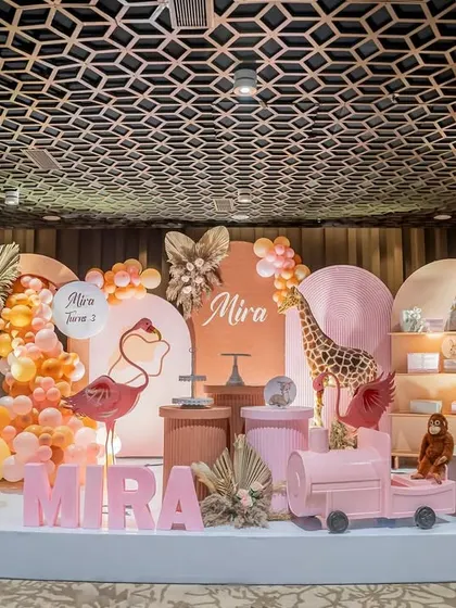 The full view of the "Pink Safari" stage, featuring marquee numbers, animal props, and a custom-designed backdrop against a unique geometric ceiling.