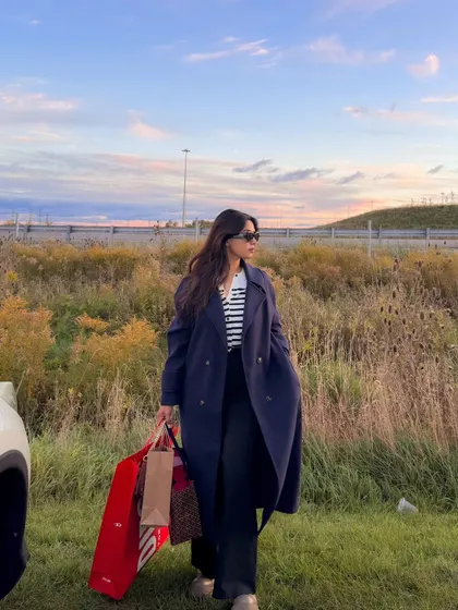 A fall shopping trip outfit, featuring a long navy trench coat and shopping bags.