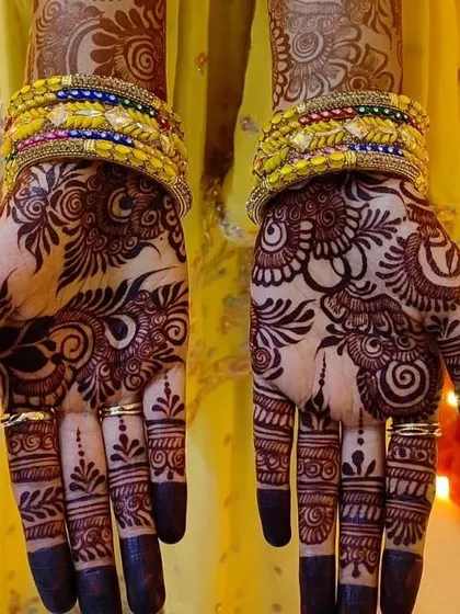 A gorgeous, dark henna stain on the palms. This Arabic-style design with full finger coverage and festive bangles is perfect for a wedding or sangeet night.