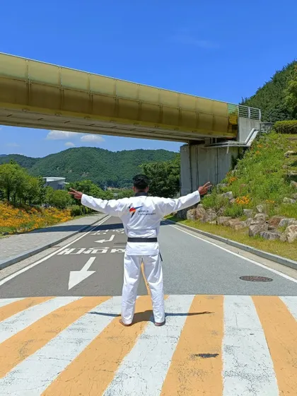 Arms outstretched, embracing the experience of being at the center of the Taekwondo world.