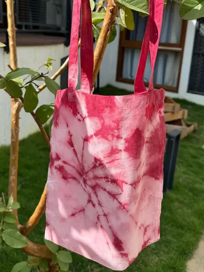 A finished tote bag from our Christmas workshop, hanging on a tree. The vibrant red is perfect for the festive season.