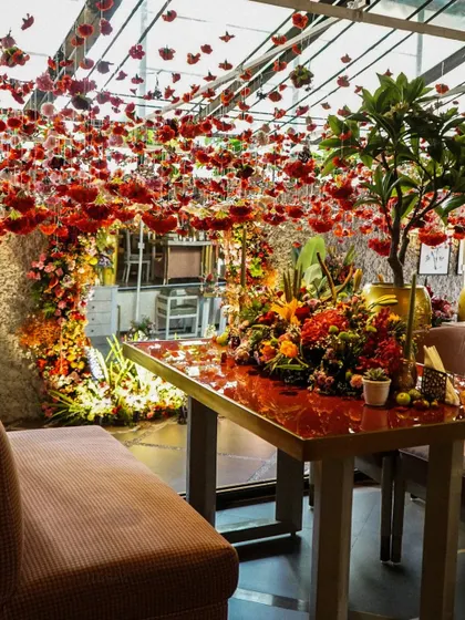 A lush and vibrant Mehendi setup at Tori Mumbai. The ceiling was covered in hanging red carnations, creating a dramatic and romantic canopy for the celebration.