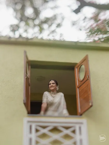 A creative shot of the bride looking out of a window, framed beautifully by the architecture.