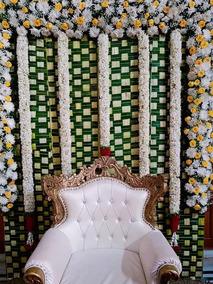 Another variation of our traditional decor for a Seemantha or naming ceremony, featuring a white and gold throne against a backdrop of woven leaves and flower garlands.