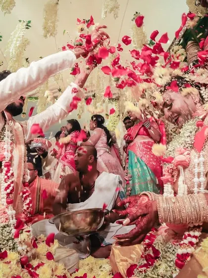 A moment frozen in time, capturing the vibrant and chaotic joy of a South Indian wedding ritual with flowers and family all around.