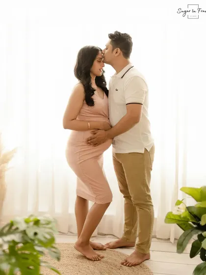 A sweet and simple maternity portrait. The husband kisses his wife's forehead as they stand in soft, natural light, creating a timeless and romantic image.
