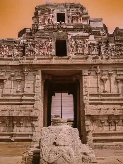 A temple facade in Hampi, edited with a warm, orange sky to create a dramatic, otherworldly feel.