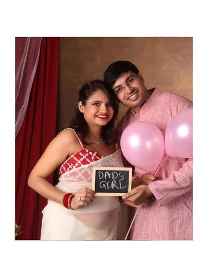 A fun gender reveal shot! This couple announces "Dad's Girl" with a chalkboard sign and pink balloons.