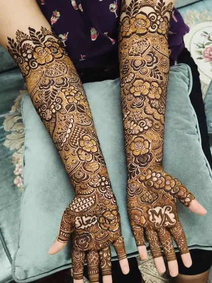 A beautiful bridal design with the couple's initials 'MK' and the groom's name 'Majaz' written on the palms.