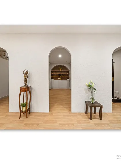 A hallway with a series of elegant archways, creating a beautiful sense of rhythm and flow. The minimalist decor and light wood flooring enhance the feeling of spaciousness and tranquility.