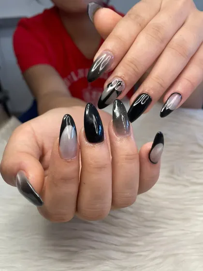 A spooky season design featuring a mix of solid black, black ombré, and abstract black French tips on almond-shaped nails.