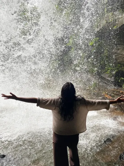 A trekker embracing the power of the waterfall, a moment of pure freedom and connection with nature.