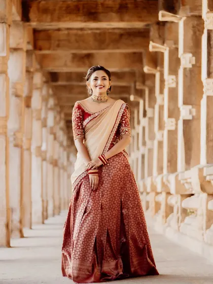 A solo portrait of the bride-to-be in the red and cream brocade half-saree. Her joyful expression shows how this outfit can make you feel special and beautiful for your pre-wedding photos.