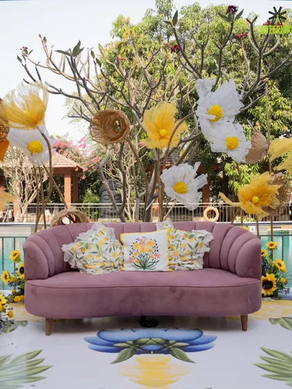 A lovely seating arrangement by the pool for a Haldi. The mauve sofa with floral cushions, set against a backdrop of oversized paper flowers, created a whimsical and comfortable spot for guests.