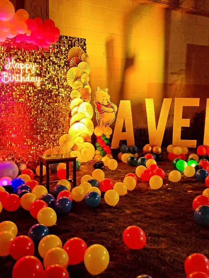 A wide view of the Winnie the Pooh party space. The floor is covered in colorful balloons, creating a fun play area for the kids, with the main stage and name letters in the background.