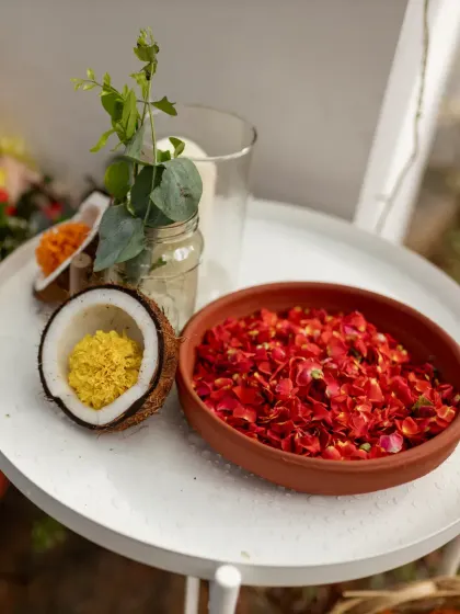 Simple, traditional elements like rose petals in an earthen bowl and flowers in a coconut shell add a beautiful, authentic touch.