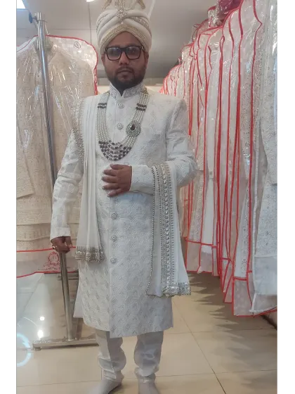 For the grooms, I offer elegant options like this pristine white embroidered sherwani. This rental comes as a complete set with a matching pagri, stole, and a layered pearl necklace.