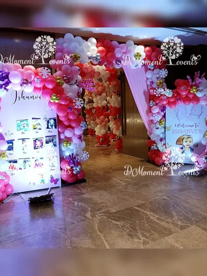 A milestone photo display for a winter-themed first birthday, set between two festive balloon arrangements.
