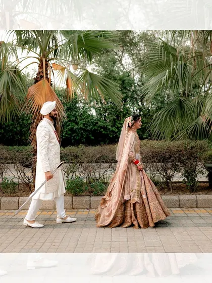A stylish walking shot of the Sikh couple, with the groom leading his bride, showcasing their regal wedding attire.