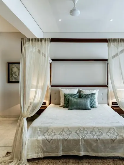 A full view of the master bedroom in the Terrazzo Residence. The elegant four-poster bed, combined with a floral armchair and soft lighting, creates a peaceful and sophisticated retreat.