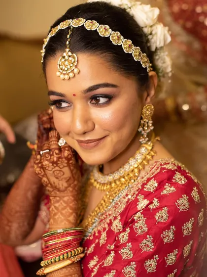 A beautiful shot of a bride on her wedding day. You can see how the intricate henna on her hands adds to her overall stunning bridal look as she puts on her jewelry.